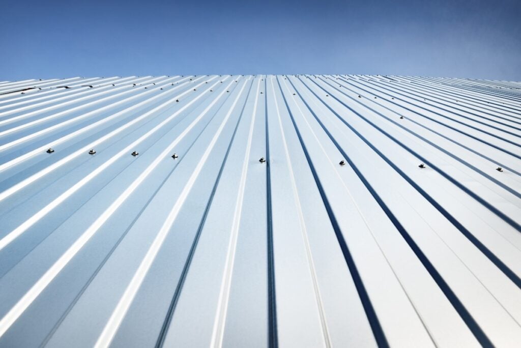 Low angle view of the silvery warehouse wall. Metal siding, texture, close-up