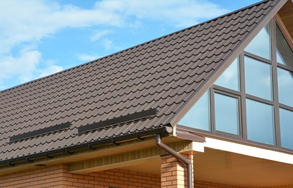 Building Modern House Construction with metal roof, rain gutter system and roof protection from snow board, snow bar (Snow guard). Roof Snow Guards: Building Materials Supplies