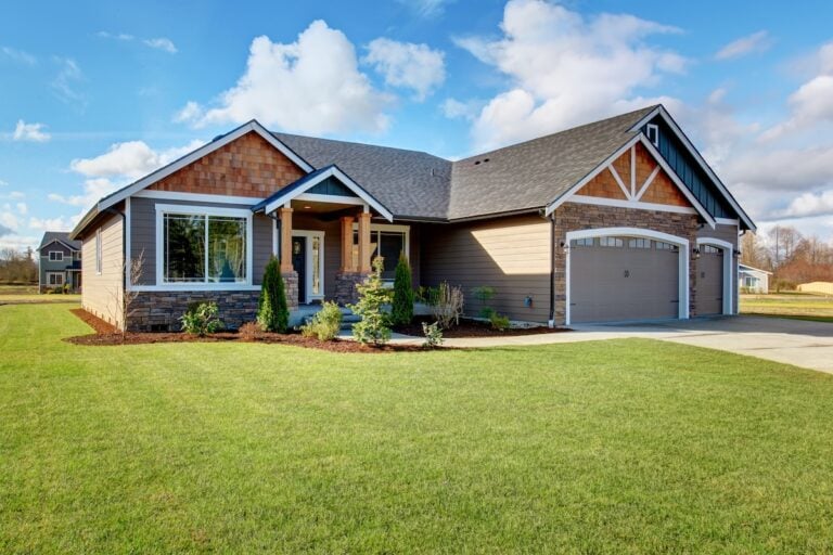 Large modern house with walkway and lots of grass.