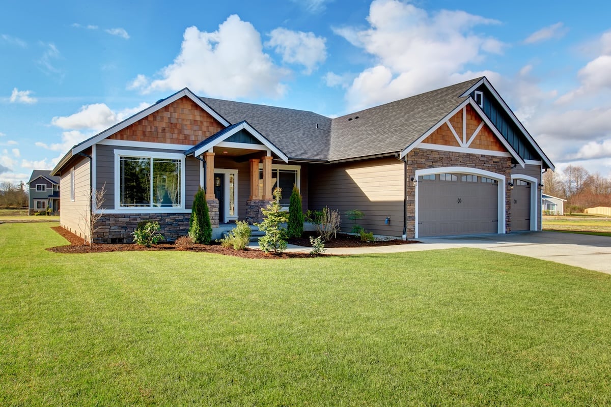 Large modern house with walkway and lots of grass.