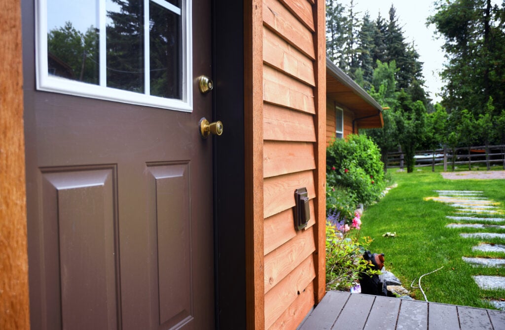 Close up of a cabin door with a garden behind it