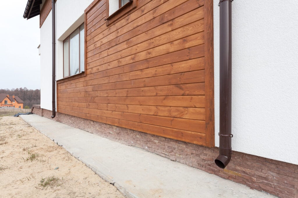 New brown copper gutter in house with white wall and wooden planks wood siding