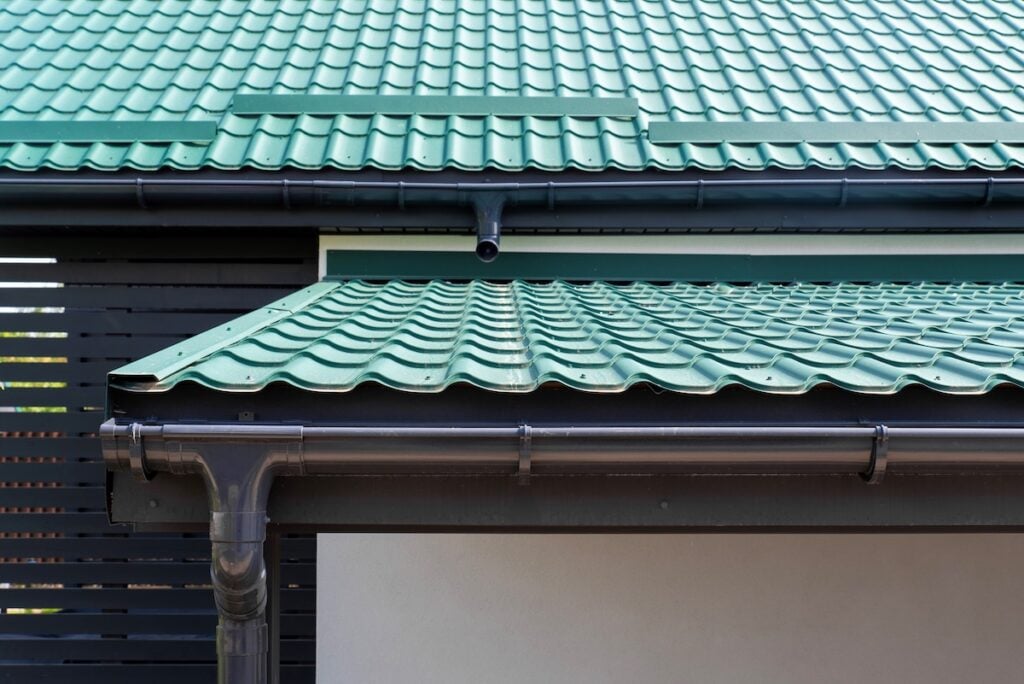 House eaves with green metal roof tile and rain gutter